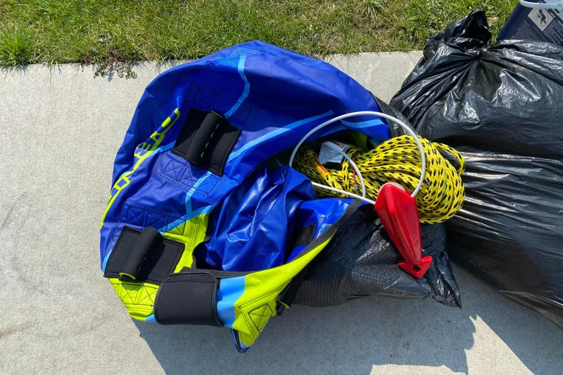 Slide: The Image of Blue and yellow inflatable tube with rope, next to black bags on concrete. - 44