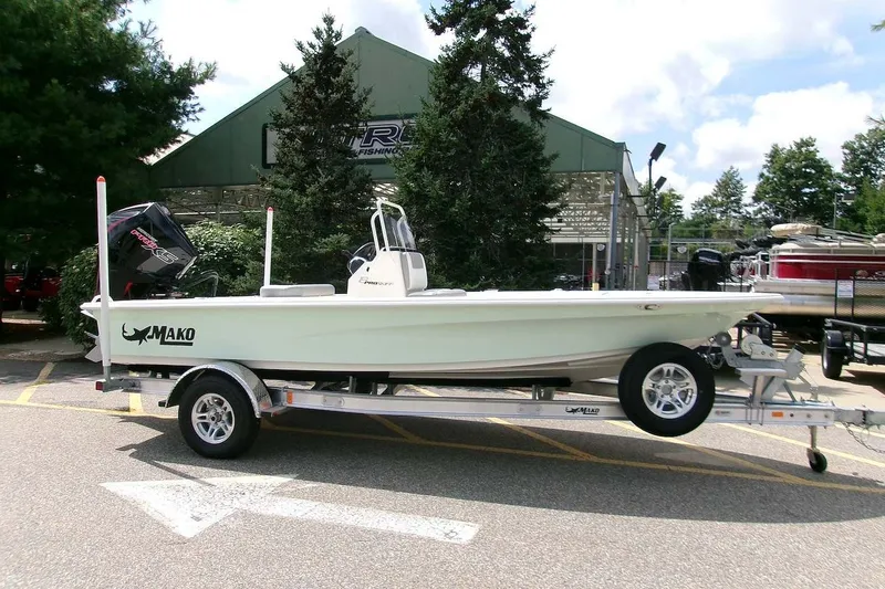 The Image of 2026 Mako 18 Pro Skiff boat on trailer, parked outdoors near trees and a building. - 0