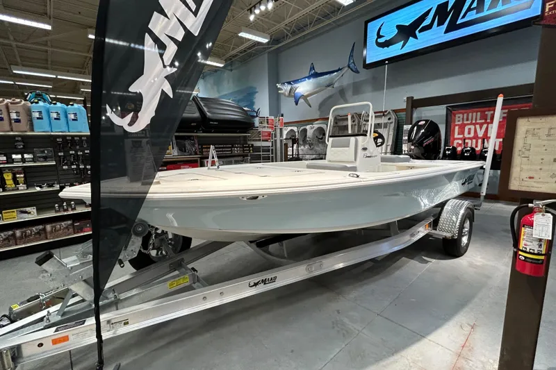 The Image of 2026 Mako 18 Pro Skiff boat displayed in a showroom with marine accessories. - 0
