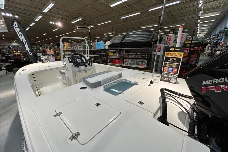 Slide: The Image of 2026 Mako 18 Pro Skiff boat displayed indoors with Mercury engine. - 2