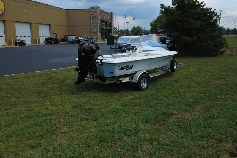 Slide: The Image of 2026 Mako 18 Pro Skiff boat on trailer, parked on grass near a building. - 8