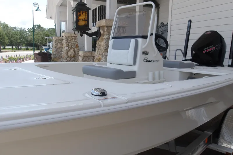 Slide: The Image of 2026 Mako 18 Pro Skiff boat with modern design, parked near a building. - 15