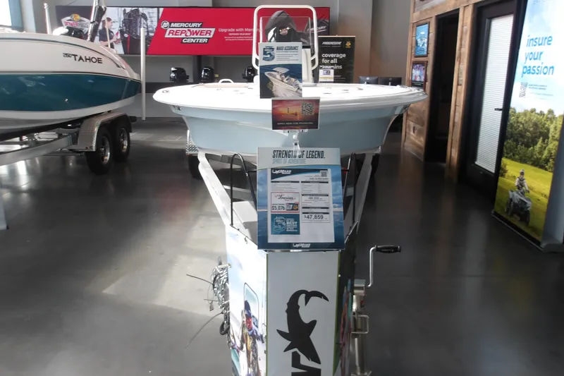 The Image of 2026 Mako 18 Pro Skiff displayed in a showroom with promotional materials. - 1