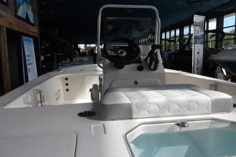 Slide: The Image of 2026 Mako 18 Pro Skiff boat interior with steering console and seating in showroom. - 11
