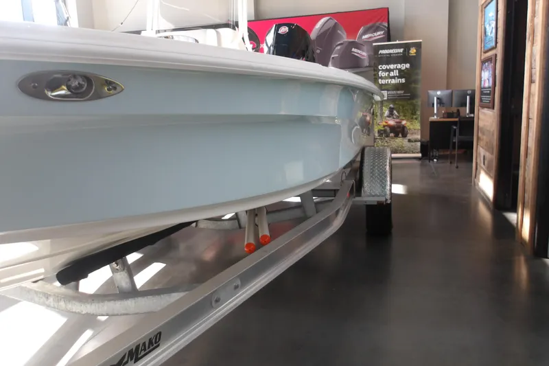 Slide: The Image of 2026 Mako 18 Pro Skiff boat on trailer in showroom setting. - 17