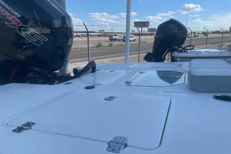 Slide: The Image of 2026 Mako 18 Pro Skiff boat with Mercury Pro XS engines, parked near a fence. - 5