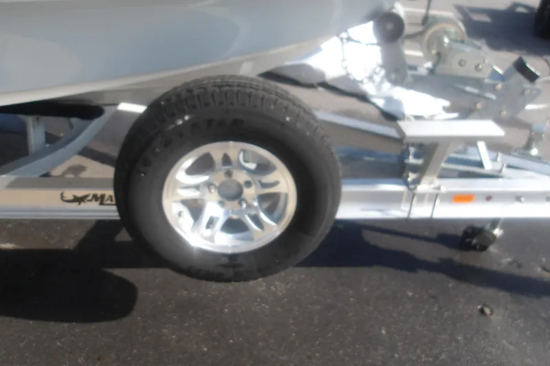 Slide: The Image of Trailer wheel of a 2026 Mako 18 Pro Skiff boat on pavement. - 16