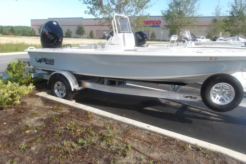 The Image of 2026 Mako 18 Pro Skiff boat on trailer, parked outdoors near a retail store. - 1