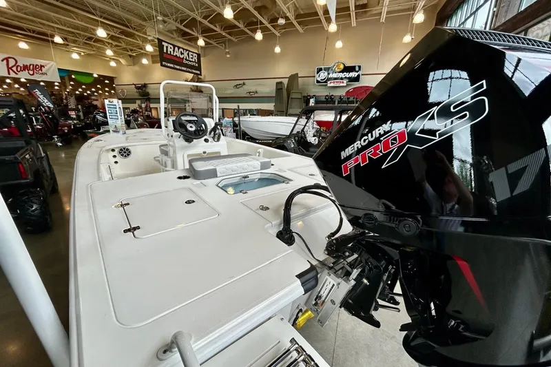 Slide: The Image of 2026 Mako Pro Skiff 18 boat on trailer in showroom, promotional sign displayed. - 4