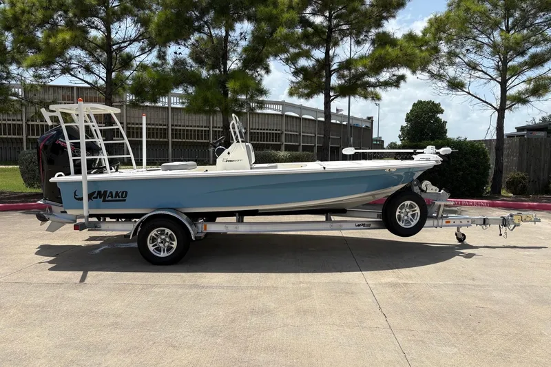 Slide: The Image of 2026 Mako 18 Pro Skiff boat on trailer, parked outdoors under trees. - 3