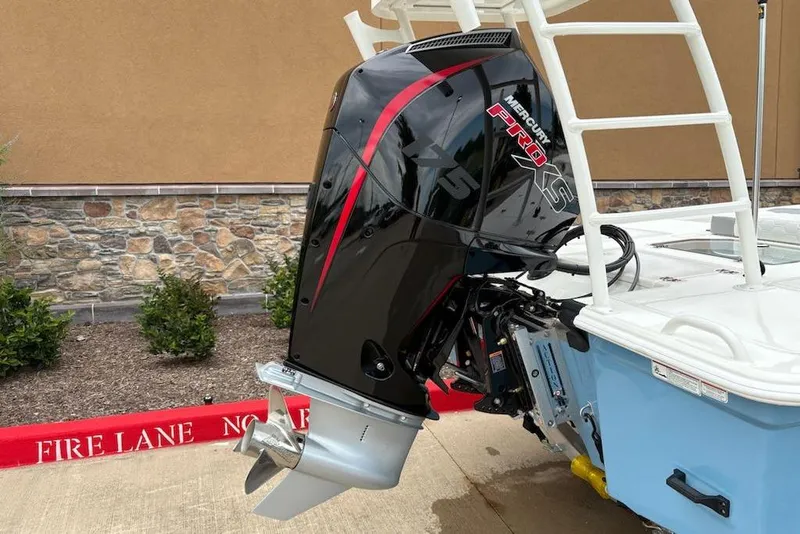Slide: The Image of 2026 Mako 18 Pro Skiff with Mercury Pro XS outboard motor, parked near stone wall. - 5