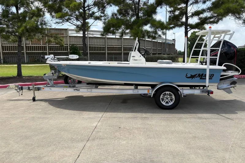 The Image of 2026 Mako 18 Pro Skiff boat on trailer, parked outdoors near trees. - 0