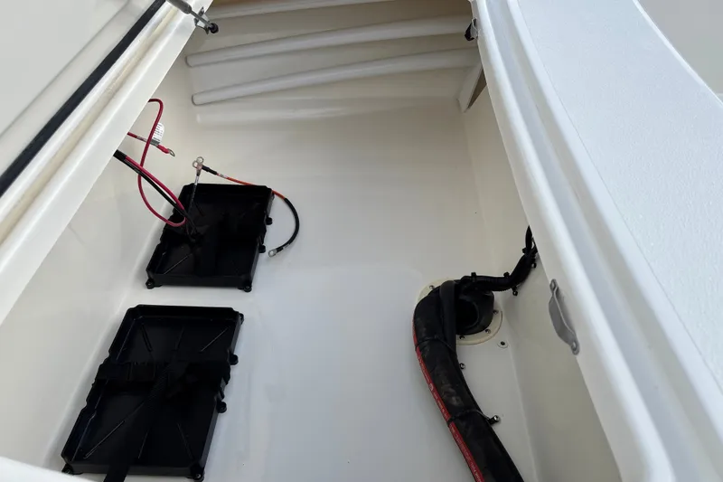 Slide: The Image of Interior view of a 2026 Mako 18 Pro Skiff boat compartment with wiring and battery trays. - 18
