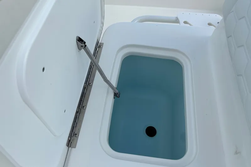Slide: The Image of Open storage compartment on 2026 Mako 18 Pro Skiff boat, featuring a sturdy hinge. - 20