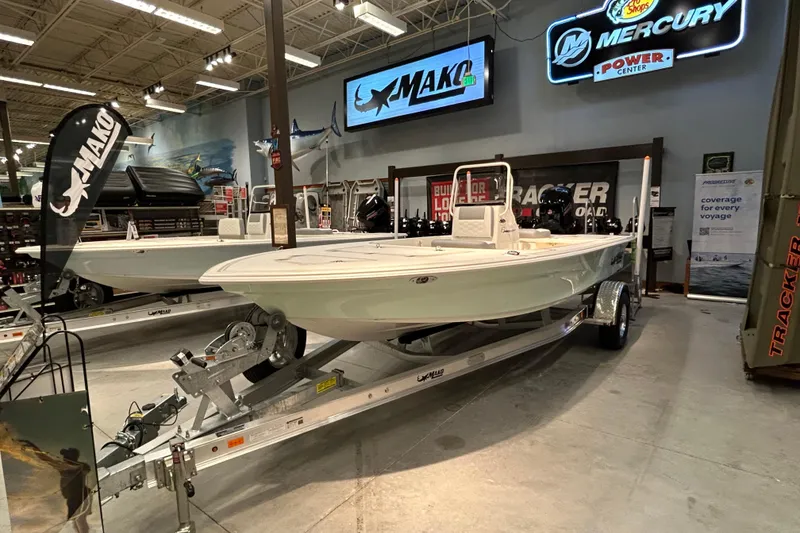 The Image of 2026 Mako 18 Pro Skiff displayed in showroom with trailer and signage. - 0