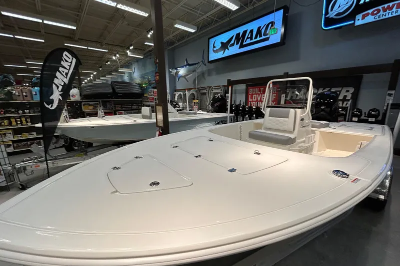 Slide: The Image of 2026 Mako 18 Pro Skiff boat displayed in a showroom with branded signage. - 2