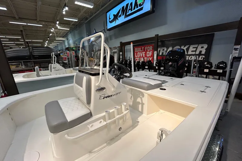 Slide: The Image of 2026 Mako 18 Pro Skiff boat displayed in showroom with seating and steering console. - 3
