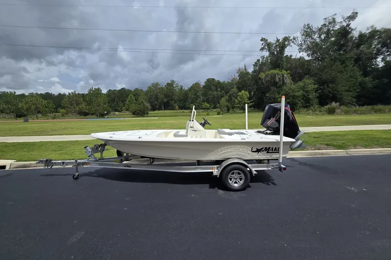 The Image of 2026 Mako 18 Pro Skiff on trailer, parked outdoors with lush greenery background. - 0