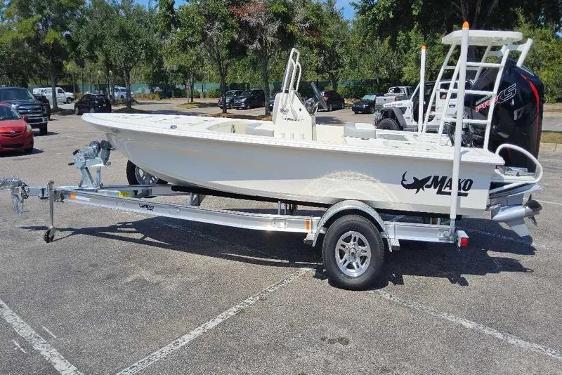 Slide: The Image of 2026 Mako Pro Skiff 18 boat on trailer in parking lot, surrounded by trees. - 1