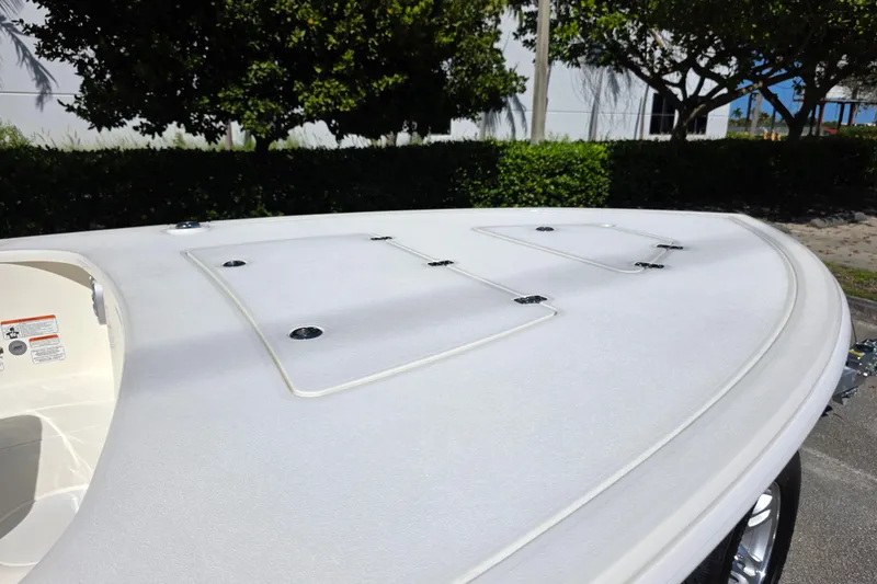 Slide: The Image of 2026 Mako 18 Pro Skiff boat deck with storage hatches, surrounded by greenery. - 3