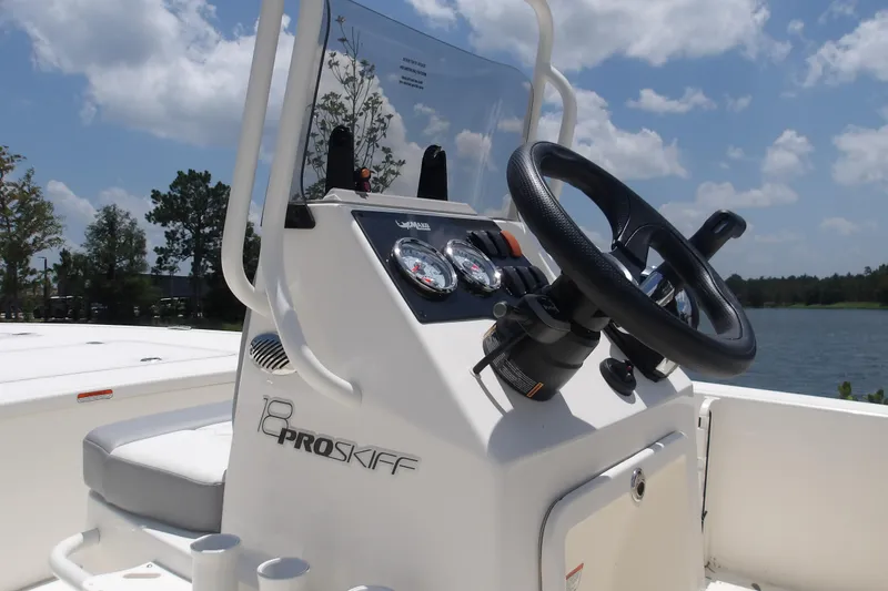 Slide: The Image of 2026 Mako 18 Pro Skiff boat console with steering wheel and gauges, set against a lake backdrop. - 17