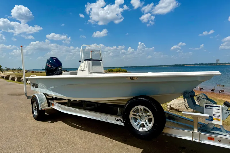 The Image of 2026 Mako 18 Pro Skiff boat on trailer by a scenic lake. - 0