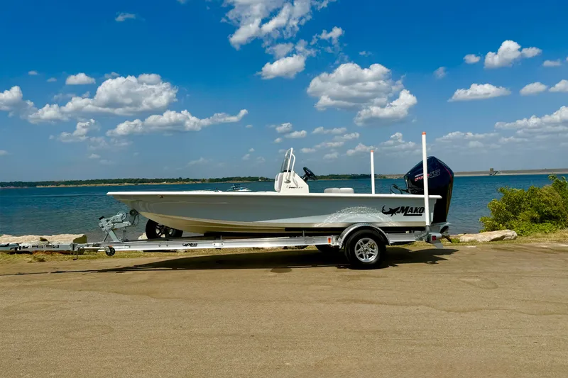 Slide: The Image of 2026 Mako 18 Pro Skiff boat on trailer by a scenic lake under blue sky. - 17