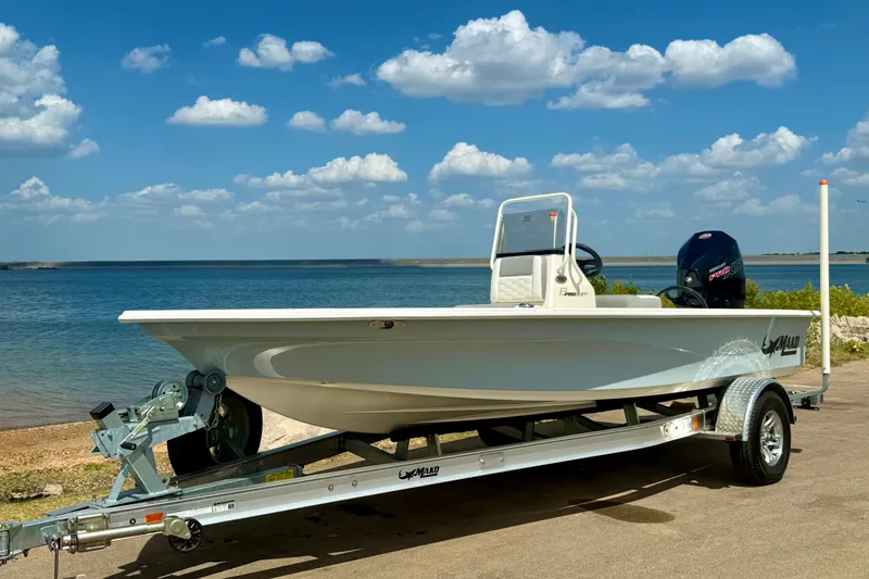 Slide: The Image of 2026 Mako 18 Pro Skiff boat on trailer by a scenic lake. - 13