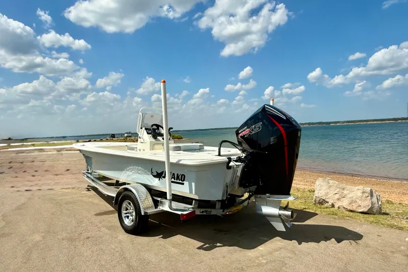 Slide: The Image of 2026 Mako 18 Pro Skiff boat on trailer by a scenic lake. - 16