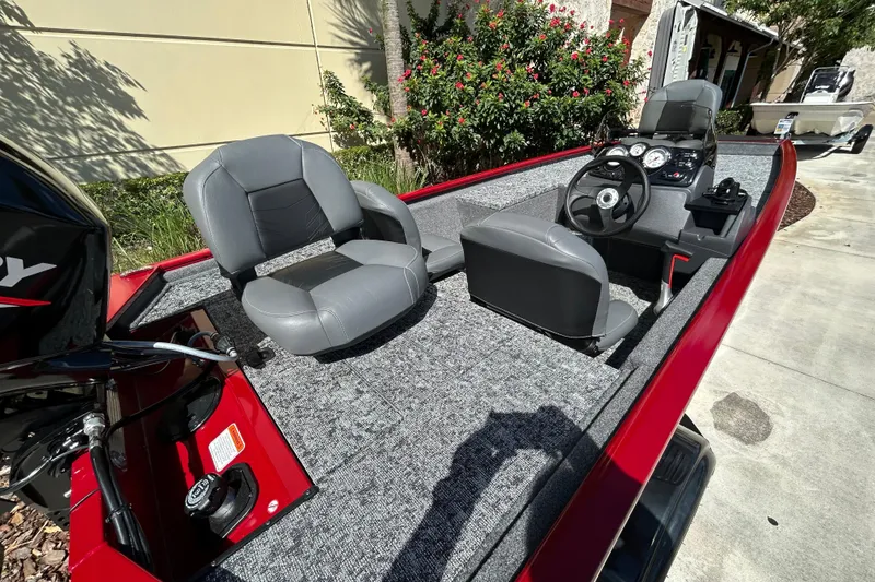 Slide: The Image of 2026 Tracker Pro 170 boat interior with gray seats and steering console, parked outdoors. - 2