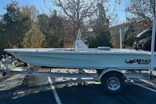 Slide: The Image of 2026 Mako 18 Pro Skiff boat on trailer, parked outdoors with trees in background. - 53