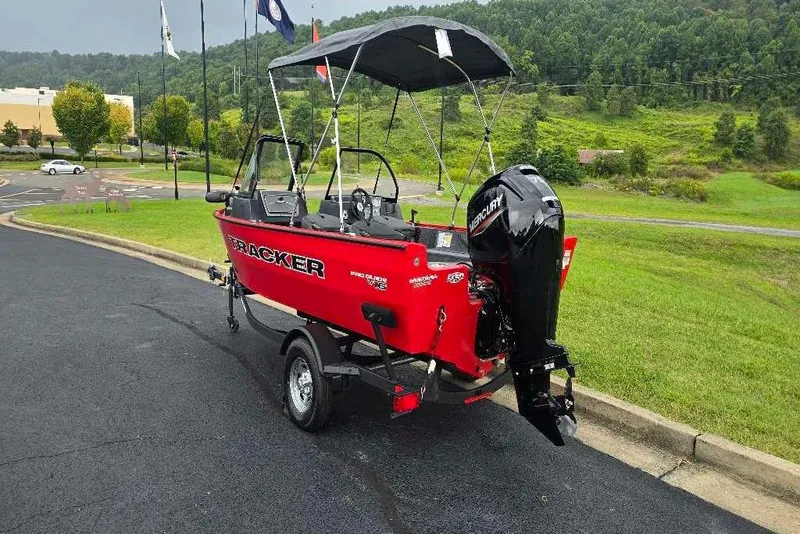 Slide: The Image of 2026 Tracker Pro Guide V-16 WT boat on trailer, red exterior, parked on road. - 2