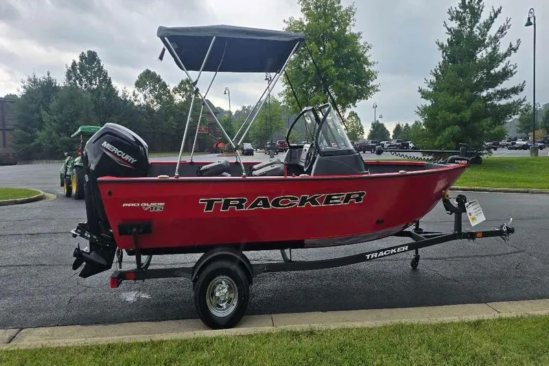 Slide: The Image of 2026 Tracker Pro Guide V-16 WT boat, red exterior, parked on a road with scenic background. - 3