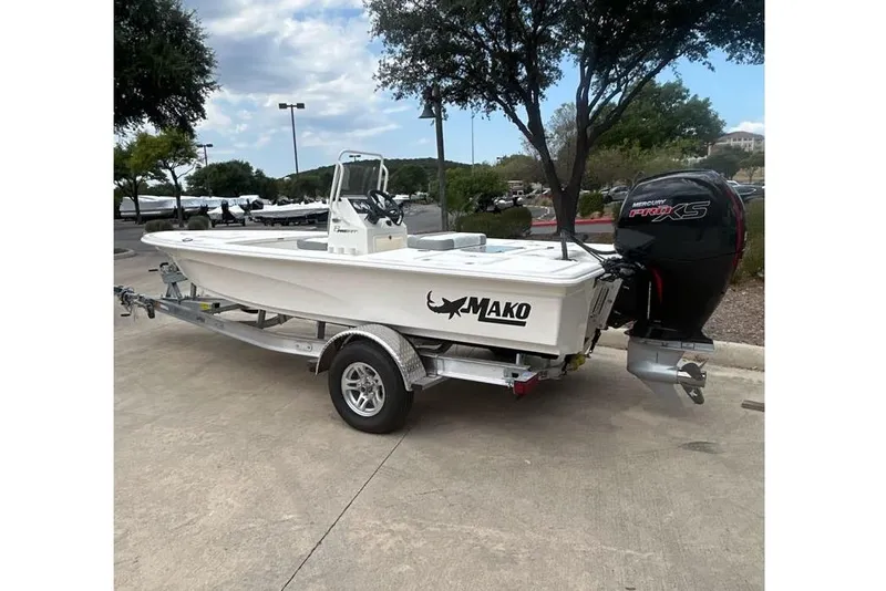 Slide: The Image of 2026 Mako Pro Skiff 18 boat on trailer, parked outdoors under trees. - 53