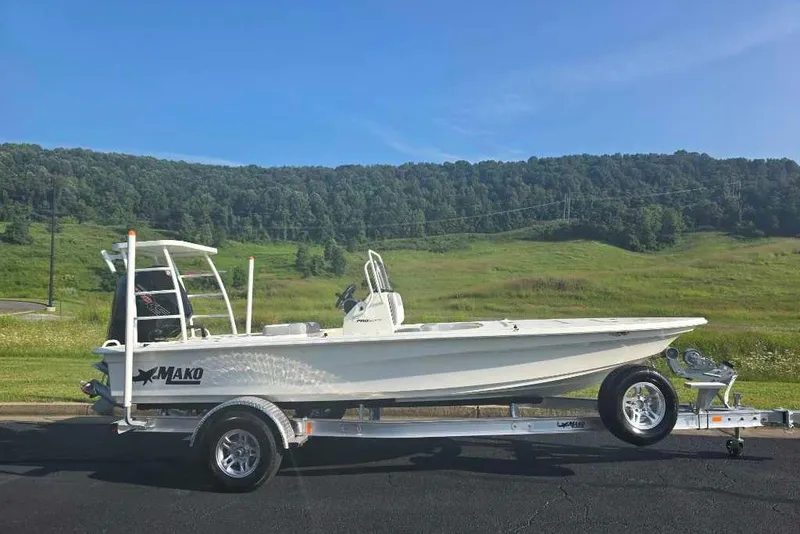 The Image of 2026 Mako 18 Pro Skiff boat on trailer, set against a scenic green landscape. - 0