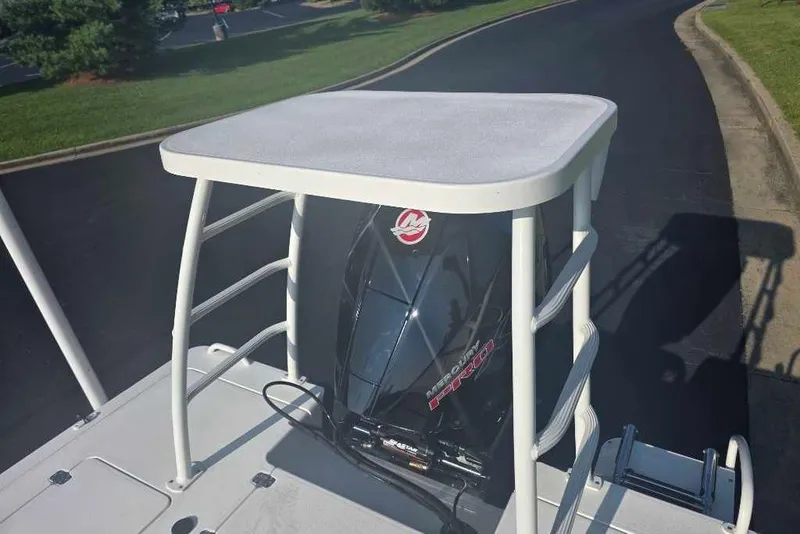 Slide: The Image of 2026 Mako 18 Pro Skiff boat with Mercury engine, parked on a paved road. - 2