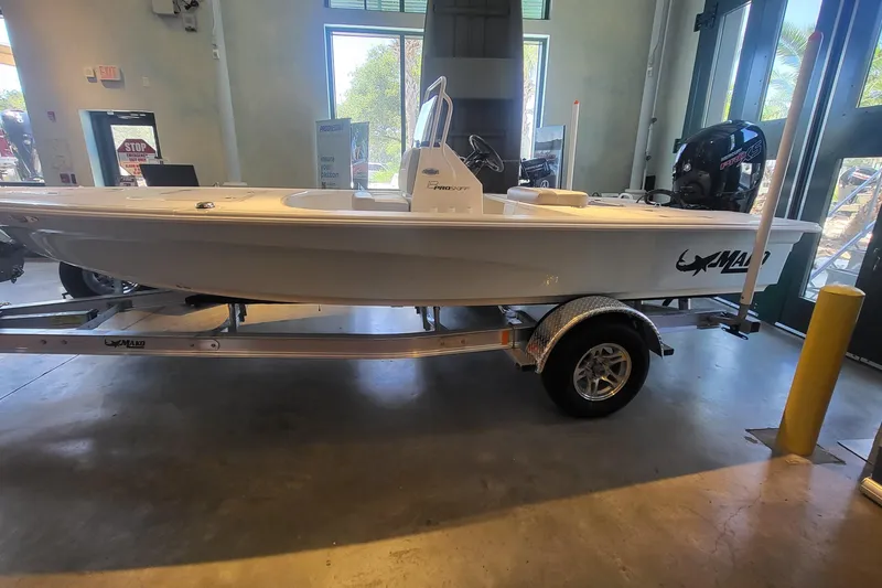 The Image of 2026 Mako Pro Skiff 18 boat on trailer in showroom, side view. - 0