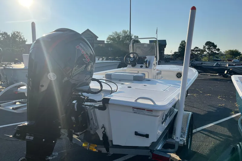 Slide: The Image of 2026 Mako 18 Pro Skiff boat with Mercury engine in a sunny parking lot. - 2