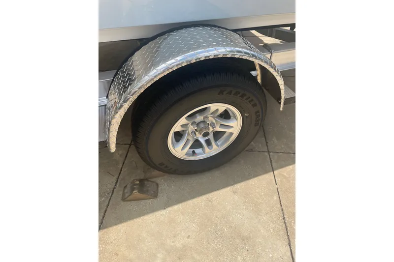 Slide: The Image of Trailer wheel of 2026 Mako 18 Pro Skiff with diamond plate fender on concrete. - 7