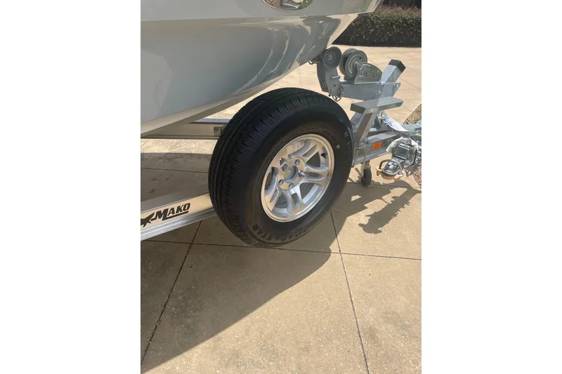 Slide: The Image of 2026 Mako 18 Pro Skiff trailer with wheel and hitch on pavement. - 9