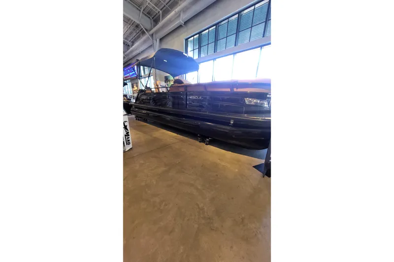 The Image of 2025 Regency 250 LE3 pontoon boat displayed indoors at a Tracker dealership. - 0