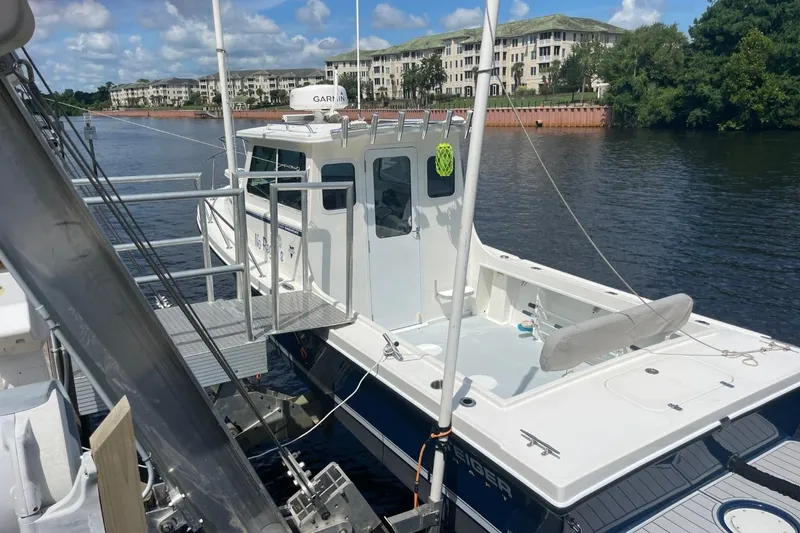 Slide: The Image of 2021 Steiger Craft 255 Chesapeake boat docked on a calm river with buildings in the background. - 10