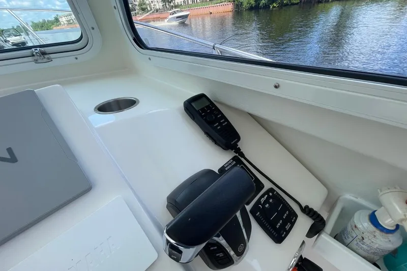 Slide: The Image of 2021 Steiger Craft 255 Chesapeake helm with controls and radio, docked by a scenic river. - 25