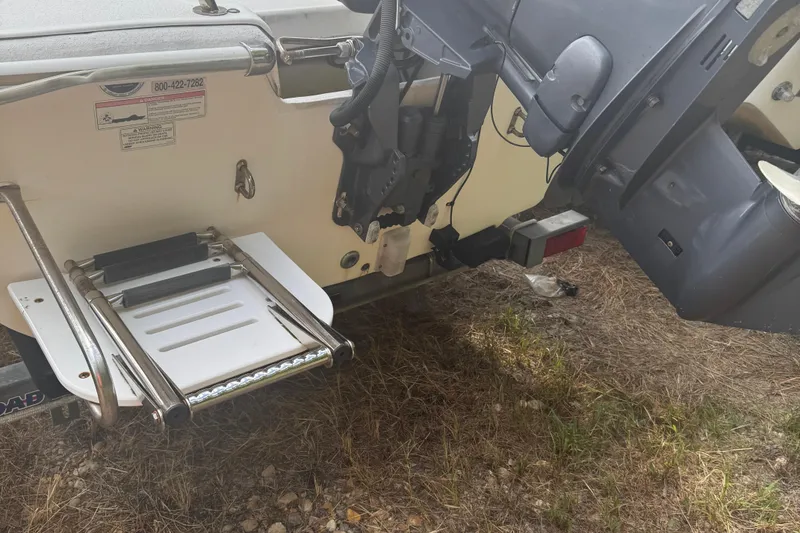 Slide: The Image of 2010 Carolina Skiff JVX16CC boat transom with motor and ladder on grassy ground. - 11
