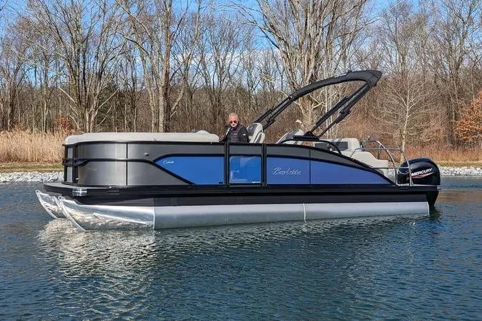 Slide: The Image of 2024 Barletta Cabrio 20UC pontoon boat on a calm lake, surrounded by trees. - 1