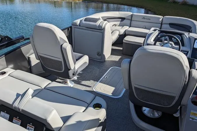 Slide: The Image of 2024 Barletta Cabrio 20UC pontoon boat interior with plush seating and steering console. - 5