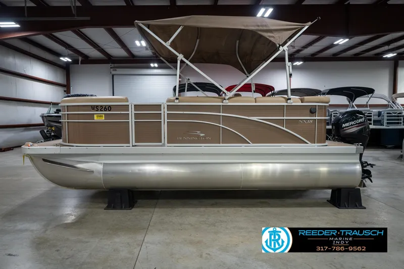 Slide: The Image of 2017 Bennington 18 SLX pontoon boat in showroom, featuring tan exterior and canopy. - 10