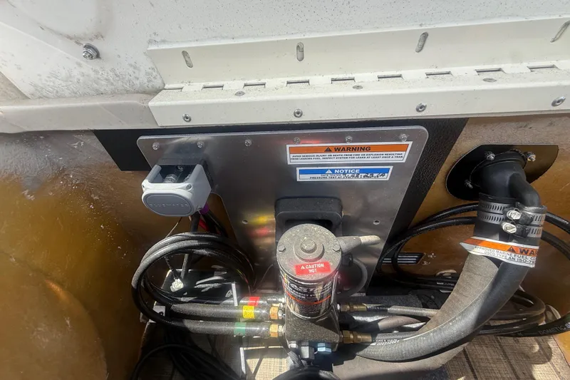 Slide: The Image of 2024 Tahoe Pontoon Grand Tahoe Elite Windshield 27' engine compartment with warning labels and cables. - 41