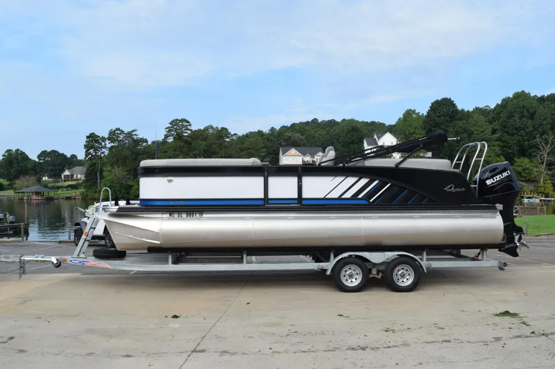 Slide: The Image of 2025 Qwest L-Class 822 RLS pontoon boat on trailer by a lake. - 1