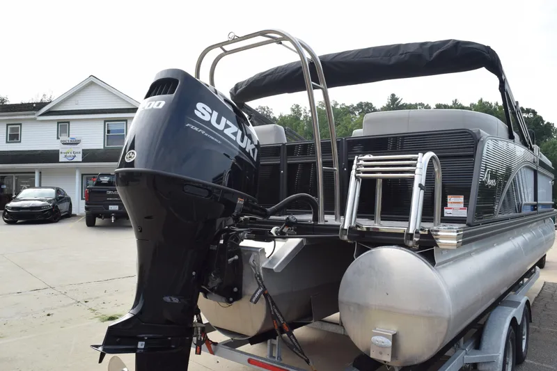 Slide: The Image of 2025 Qwest L-Class 822 RLS pontoon boat with Suzuki engine, parked at dealership. - 5